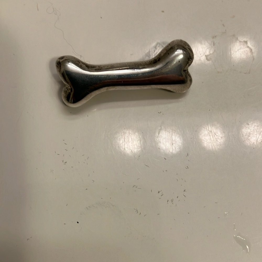 Silver dog bone pin measuring just over 1” long and almost 1/4” wide.